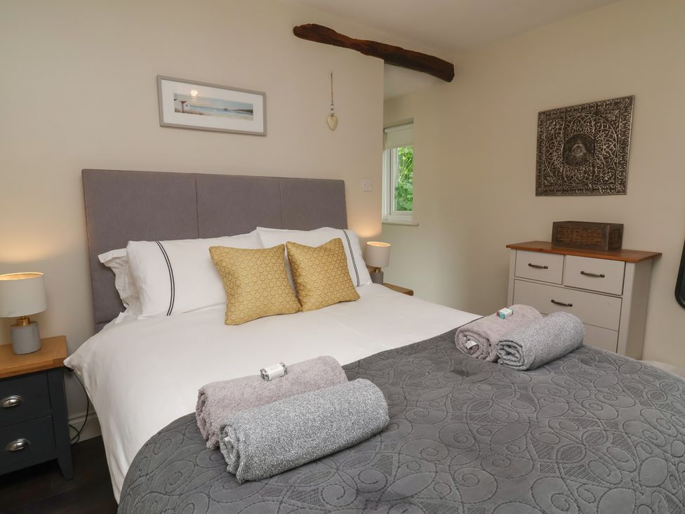 A bedroom with a bed and dresser at Quay Close Cottage