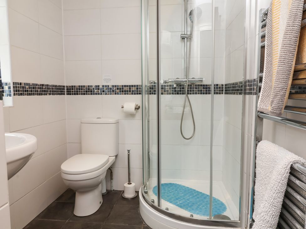 A bathroom featuring a shower, toilet, and sink at Quay Close Cottage