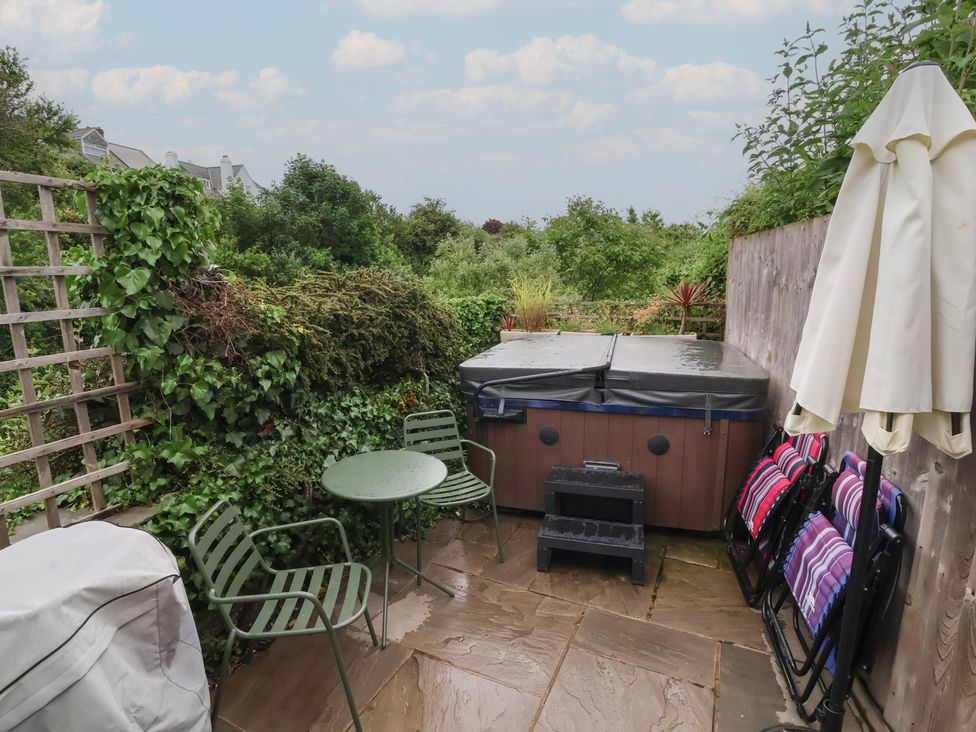 A garden with a hot tub and seating area at Quay Close Cottage
