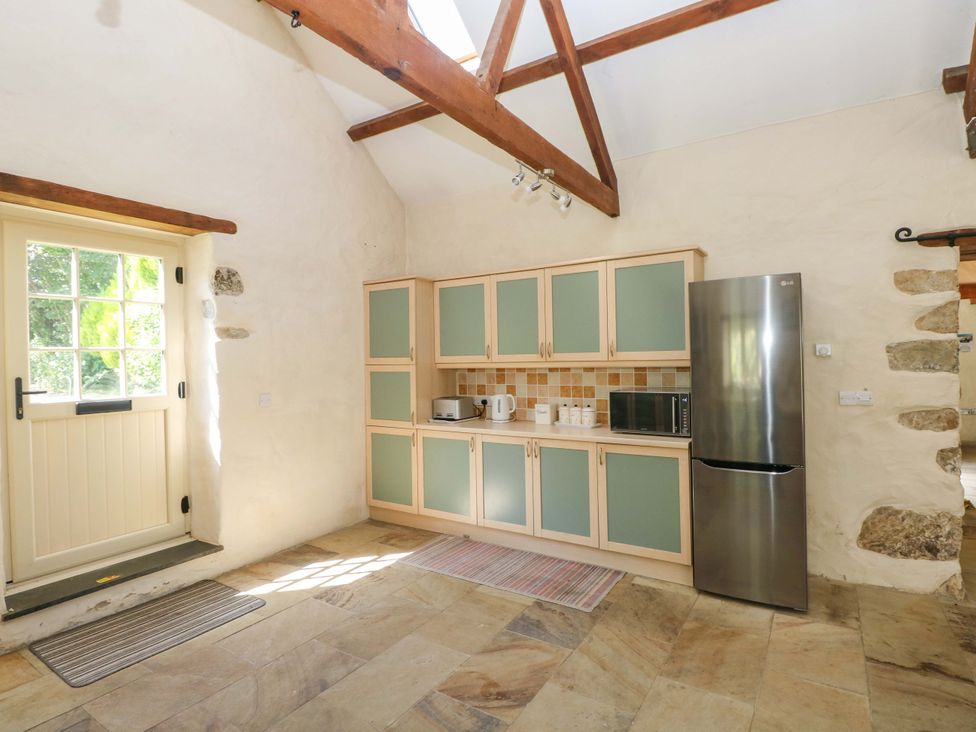 A kitchen with cabinets, a fridge, and a door at Carreg Las in Haverfordwest