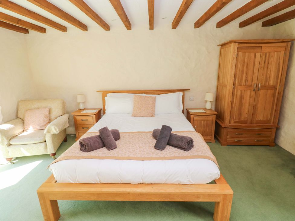 A bedroom with a bed and armchair at Carreg Las in Haverfordwest