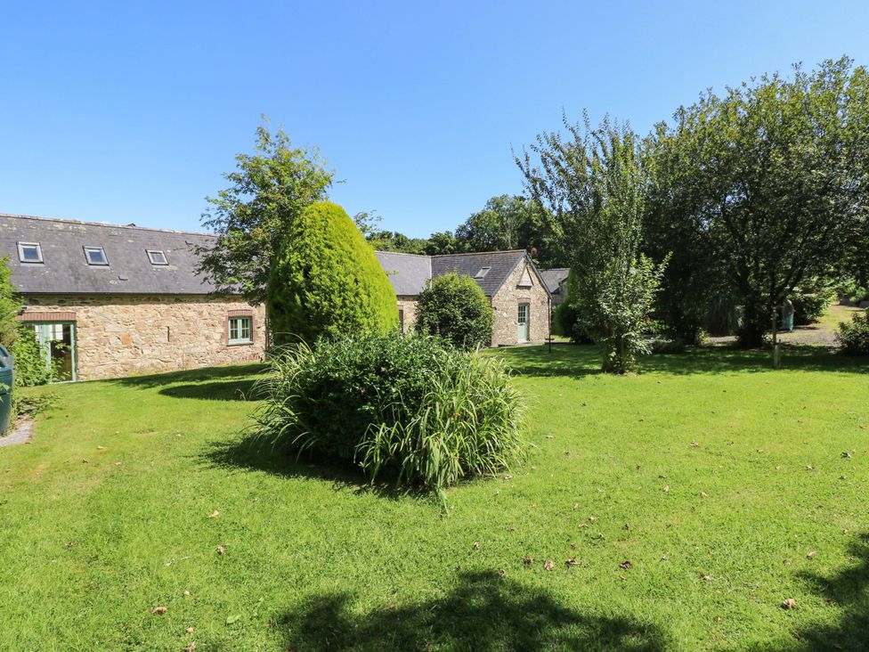 A garden with stone buildings and trees at Carreg Las in Haverfordwest