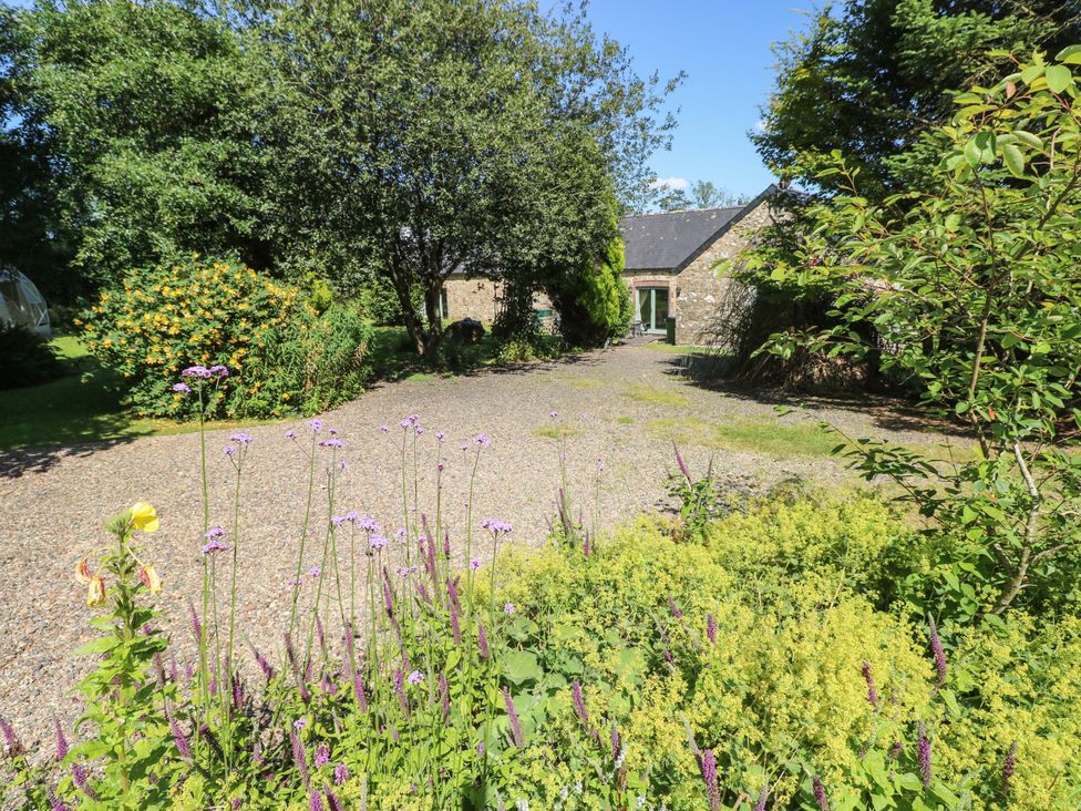 A garden with flowers and a stone building at Carreg Las in Haverfordwest