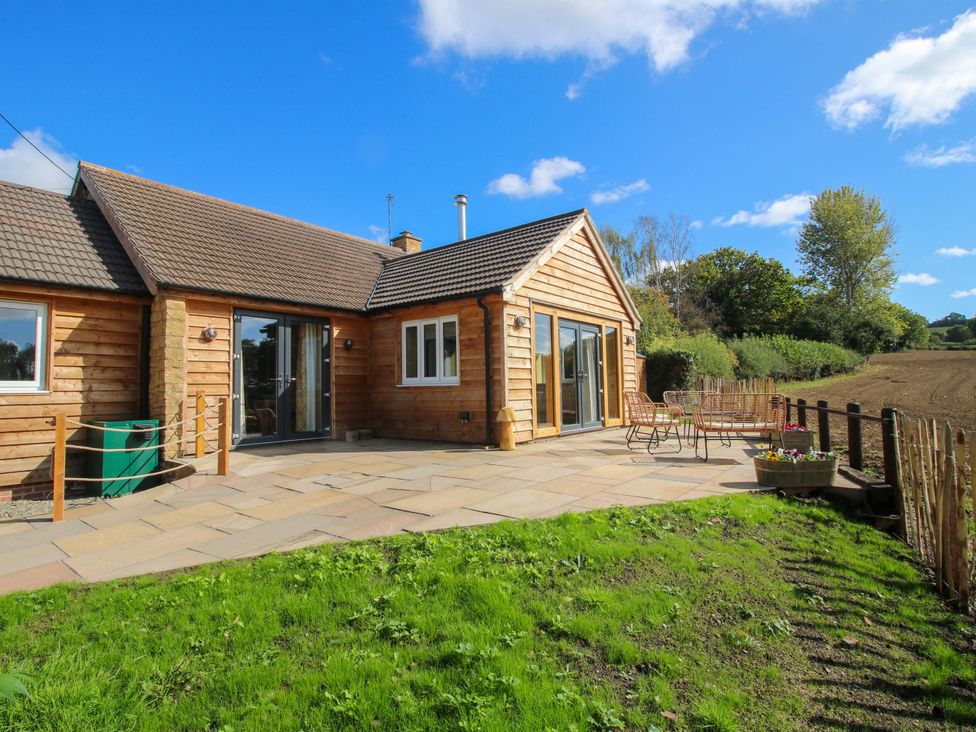 A wooden house with a patio and garden furniture at Dingle in Cleobury Mortimer