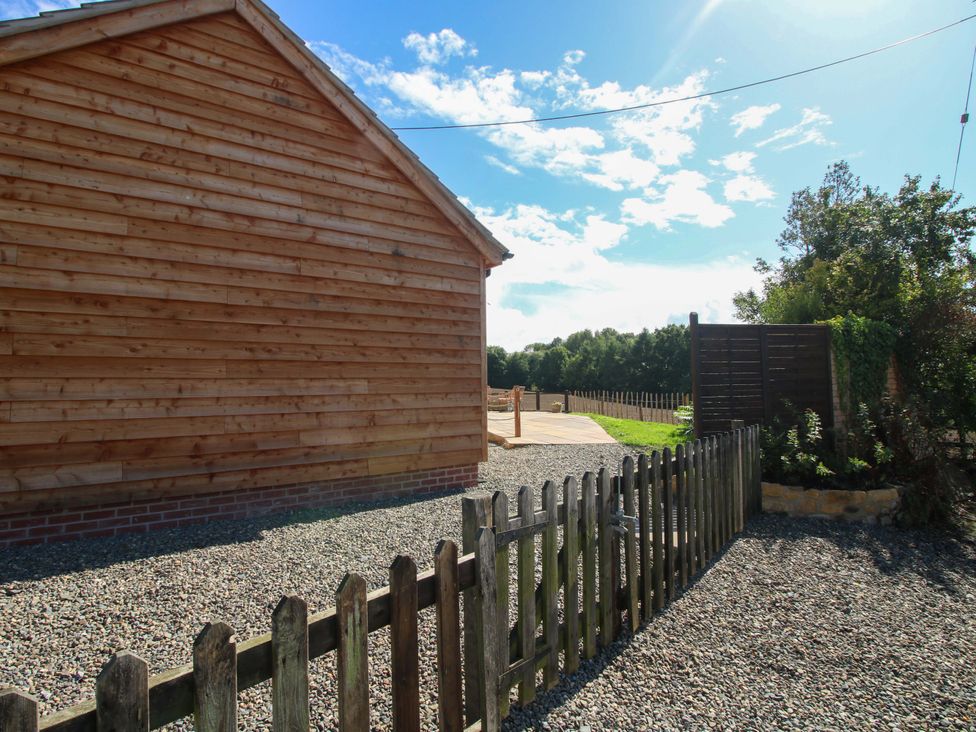 An outdoor area with a wooden building and fence at Dingle in Cleobury Mortimer