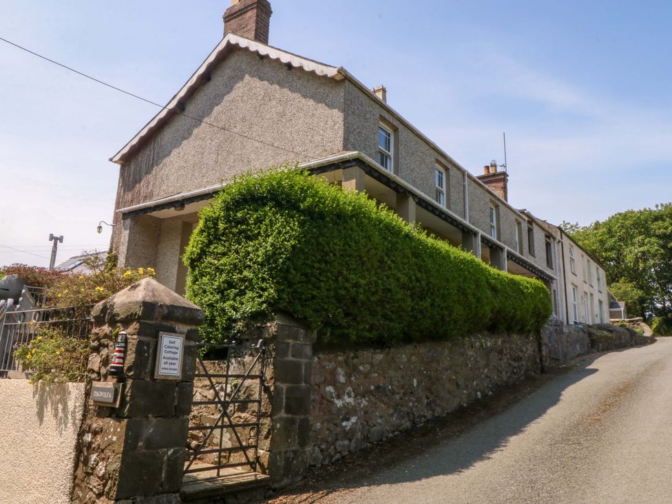 A house with a hedge and gate in front at Disgwylfa, Sarn Mellteyrn