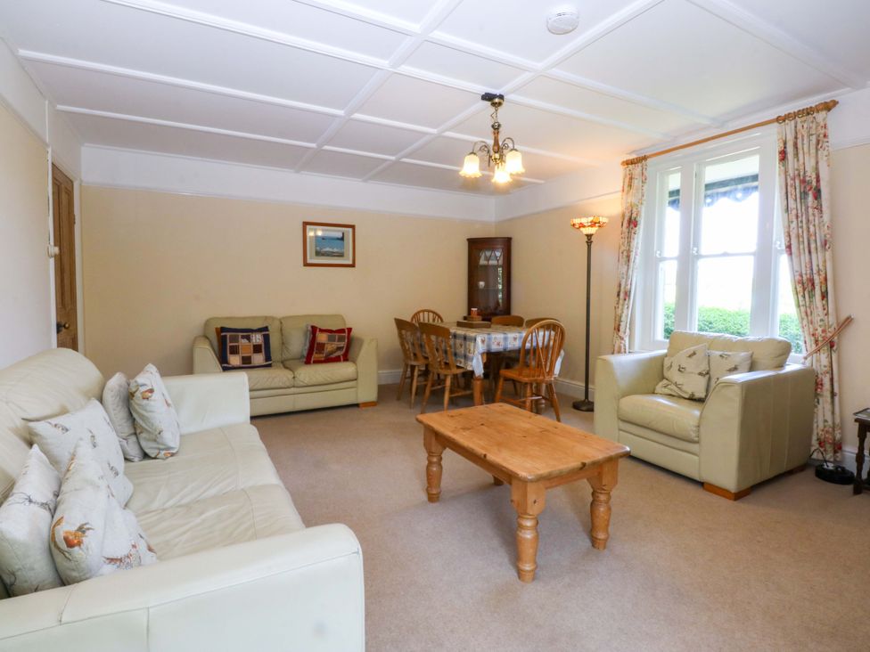 A living room with a sofa, armchairs, and a dining table at Disgwylfa Sarn Mellteyrn