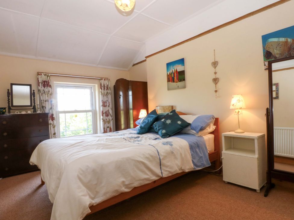 A bedroom with a bed and a dresser at Disgwylfa Sarn Mellteyrn