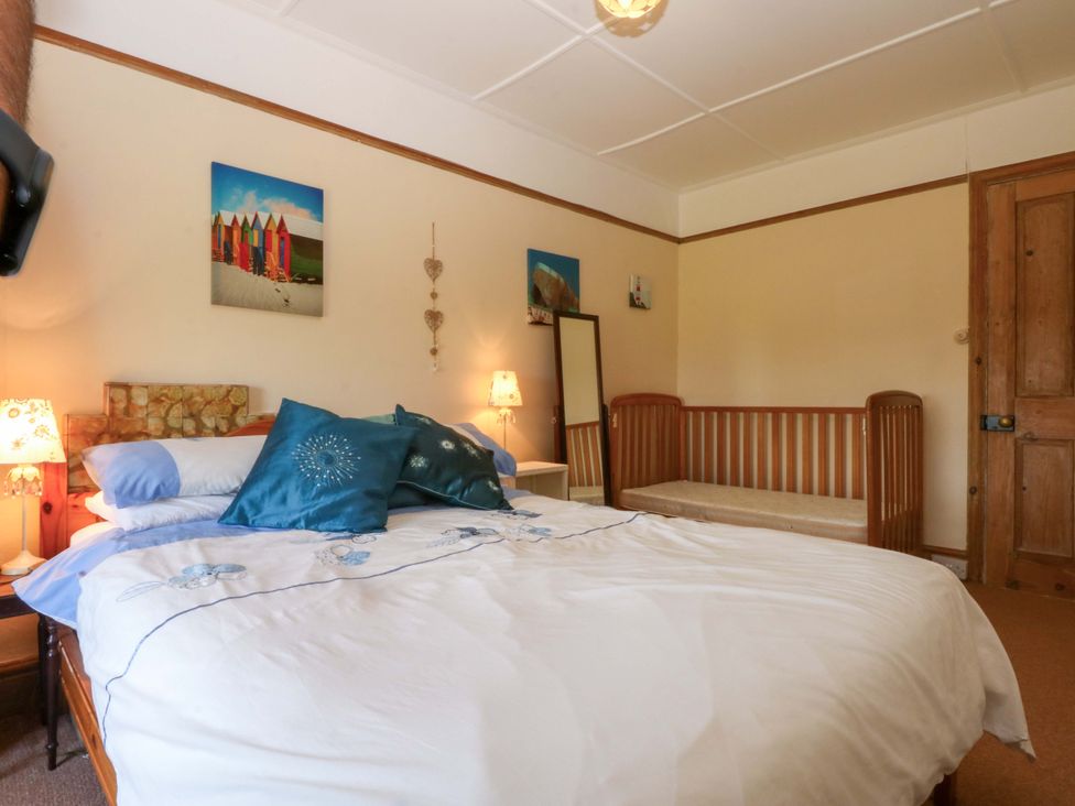 A bedroom with a bed and a wooden bench at Disgwylfa in Sarn Mellteyrn