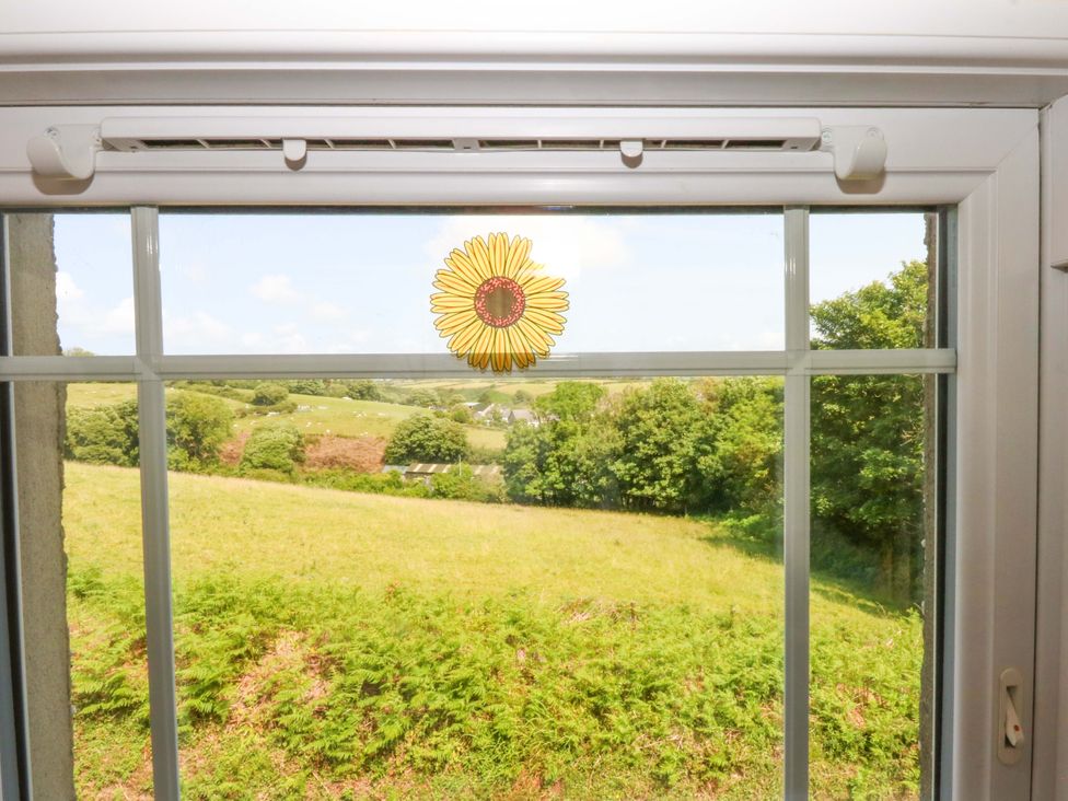 A window with a sunflower sticker and a view of greenery at Disgwylfa in Sarn Mellteyrn