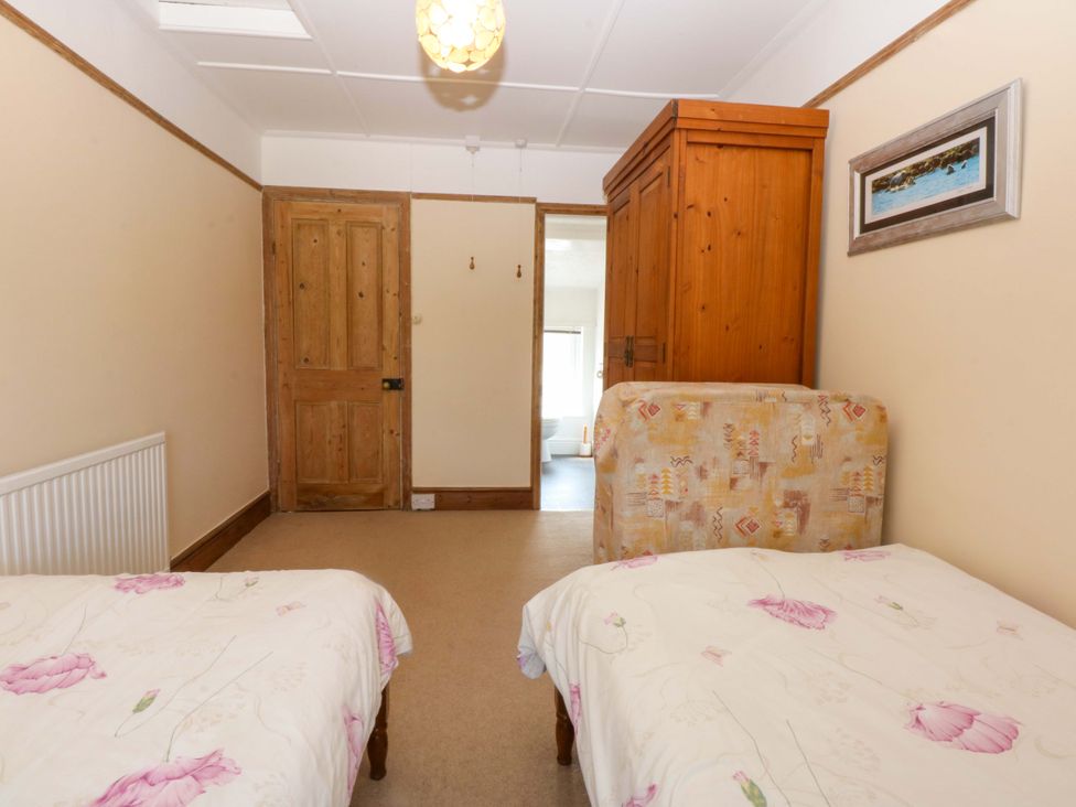 A bedroom with two beds and a wardrobe at Disgwylfa Sarn Mellteyrn