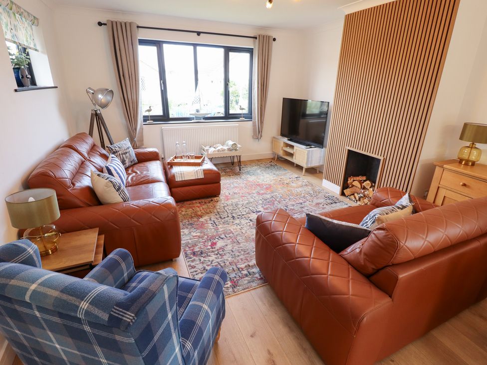 A living room with sofas and a television at Sandy Toes in Trusthorpe