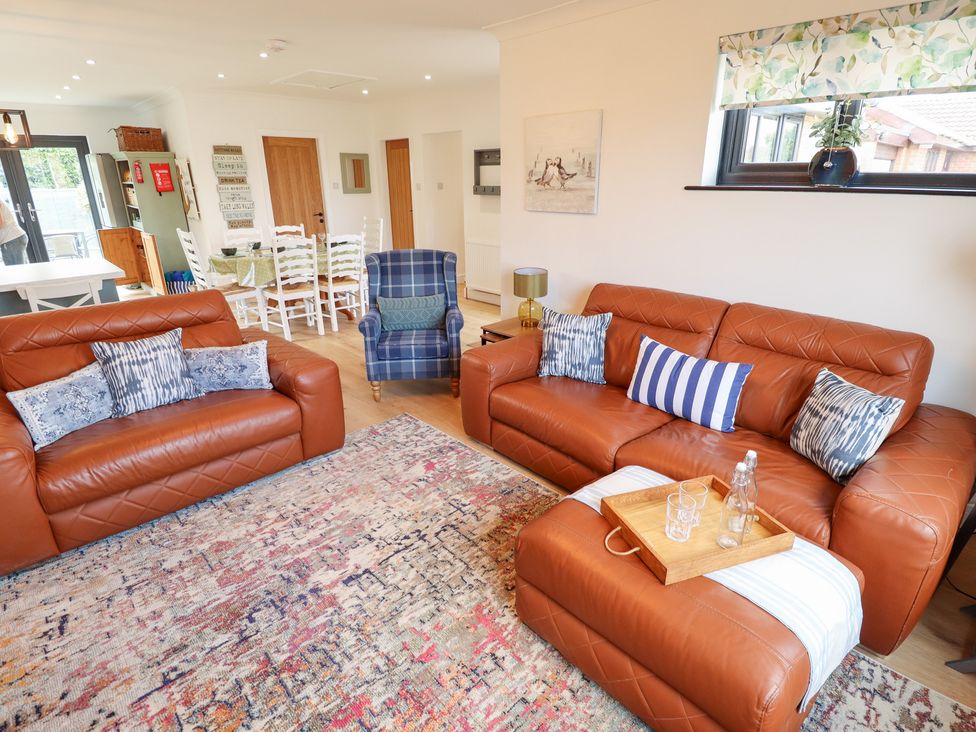 A living room with sofas and a dining area at Sandy Toes in Trusthorpe
