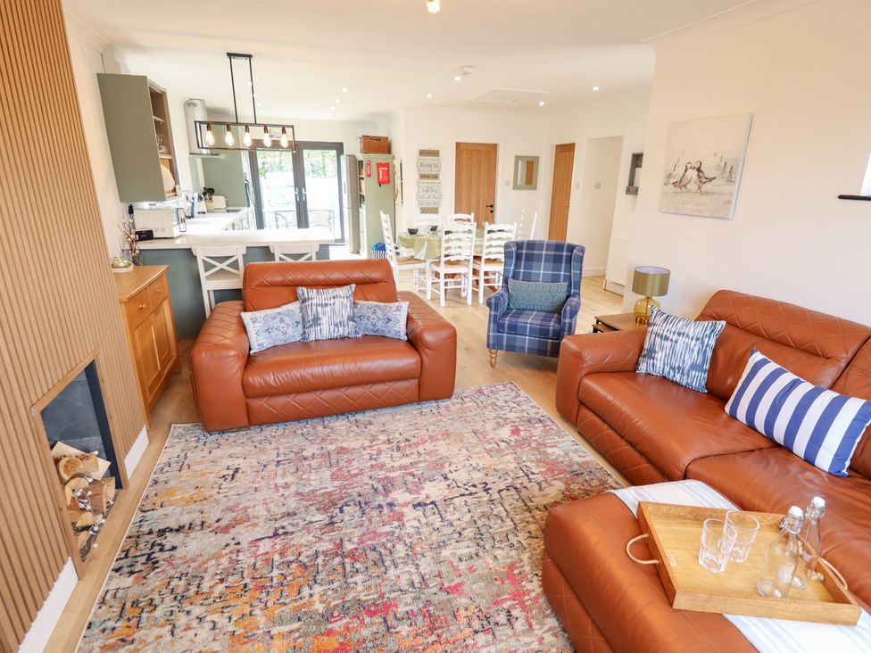 A living room with brown sofas and a dining area at Sandy Toes in Trusthorpe