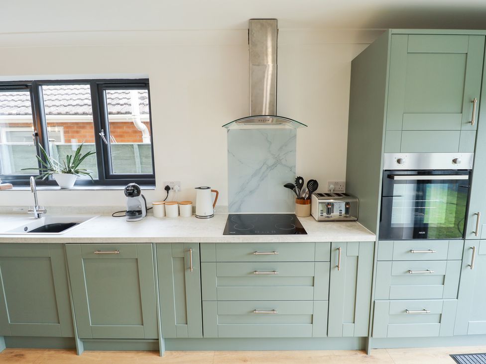 A kitchen with sink, stove, cabinets, coffee maker, and utensils holder at Sandy Toes in Trusthorpe