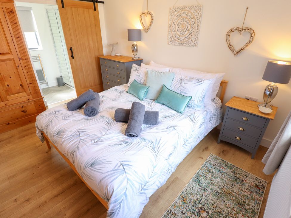 A bedroom with a bed and nightstand at Sandy Toes in Trusthorpe