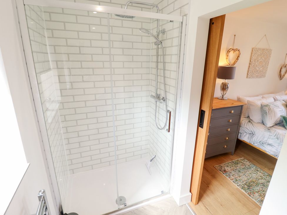 A shower with tile walls and an open door leading to a bedroom at Sandy Toes in Trusthorpe