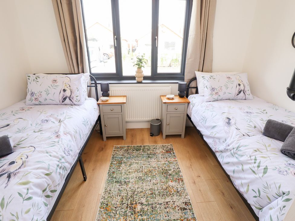 A bedroom with two beds and a window at Sandy Toes in Trusthorpe