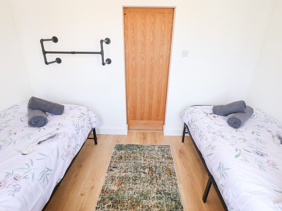 A bedroom with two beds and a wooden door at Sandy Toes in Trusthorpe