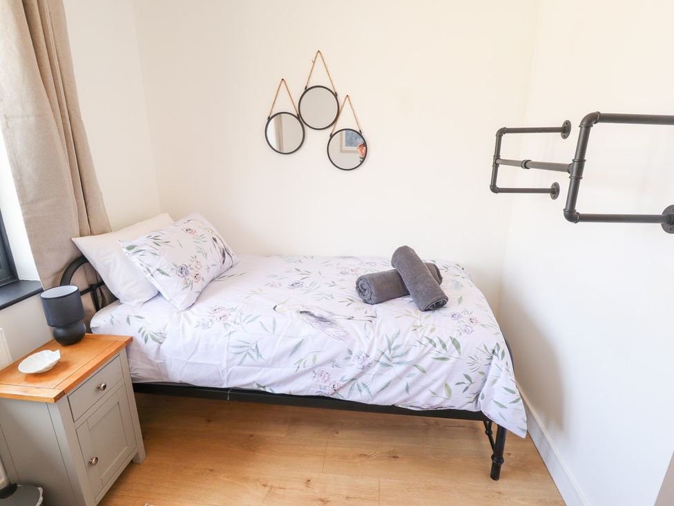 A bedroom with a bed and nightstand at Sandy Toes in Trusthorpe