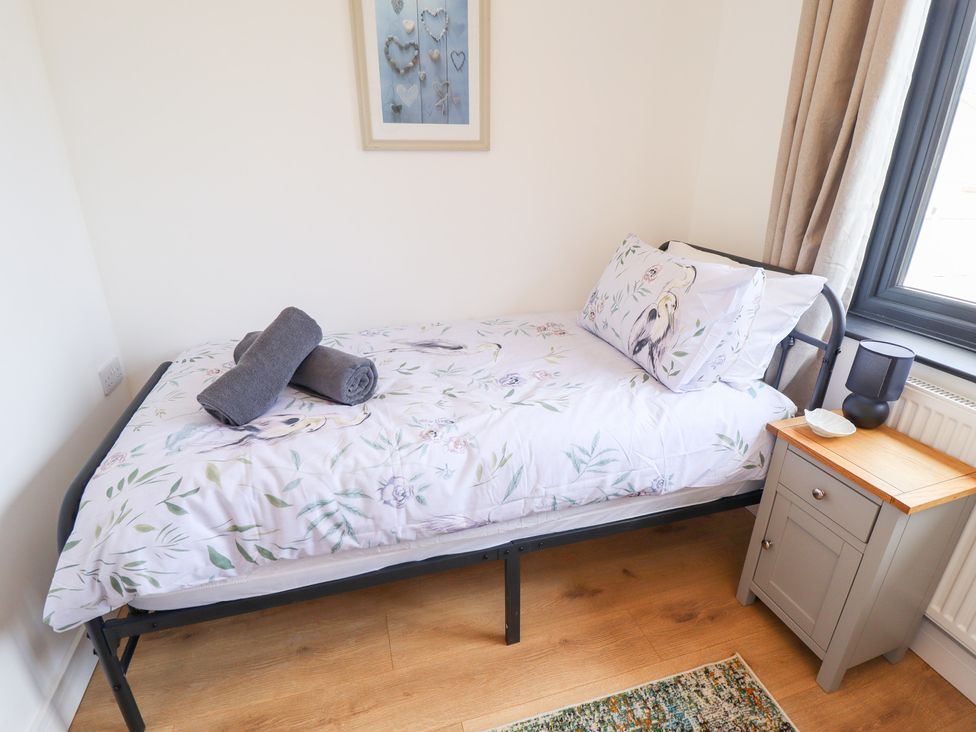 A bedroom with a bed, towel, and nightstand at Sandy Toes in Trusthorpe