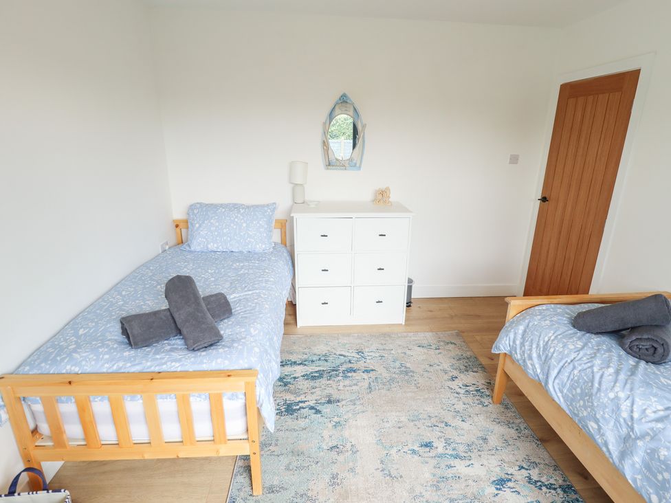 A bedroom with two beds and a dresser at Sandy Toes in Trusthorpe