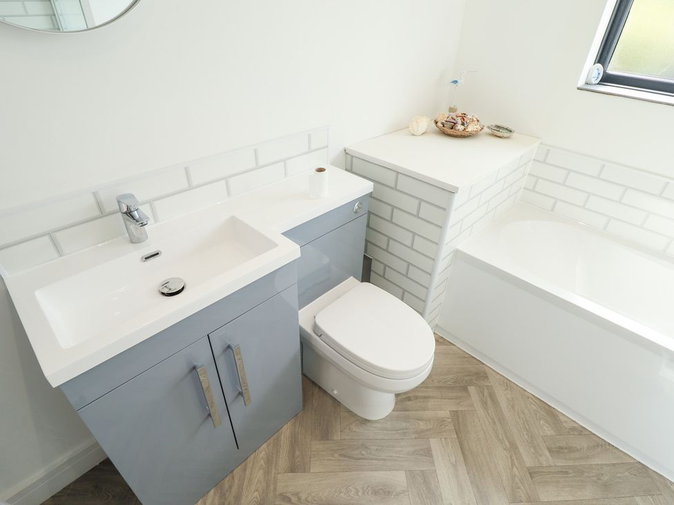 A bathroom with a washbasin, toilet, and bathtub at Sandy Toes in Trusthorpe