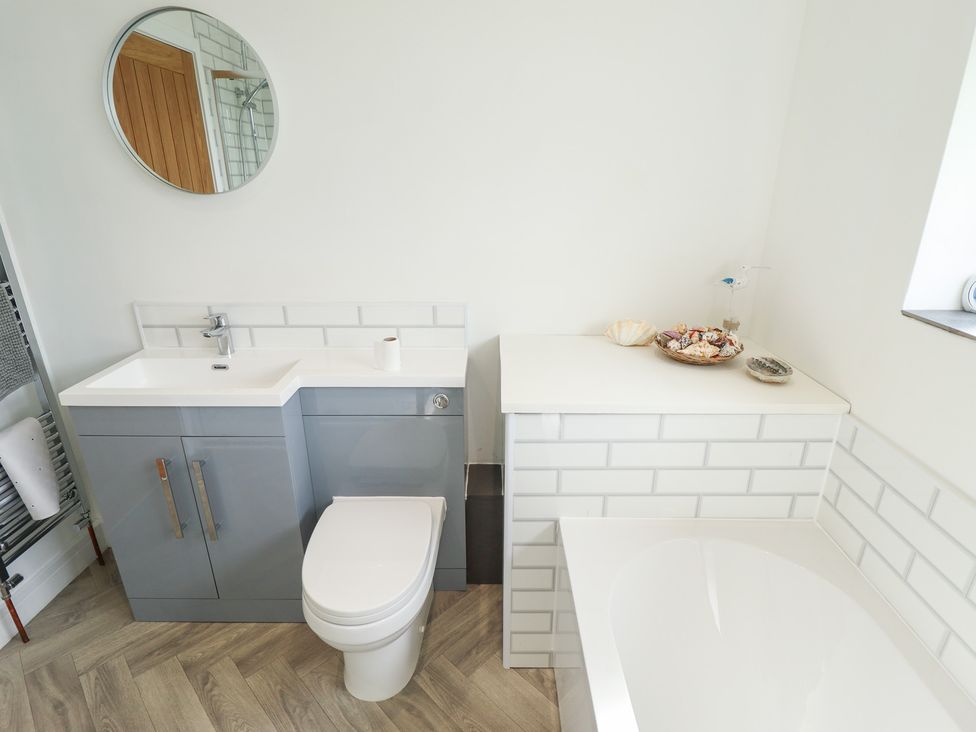A bathroom with a sink, toilet, and bath at Sandy Toes in Trusthorpe