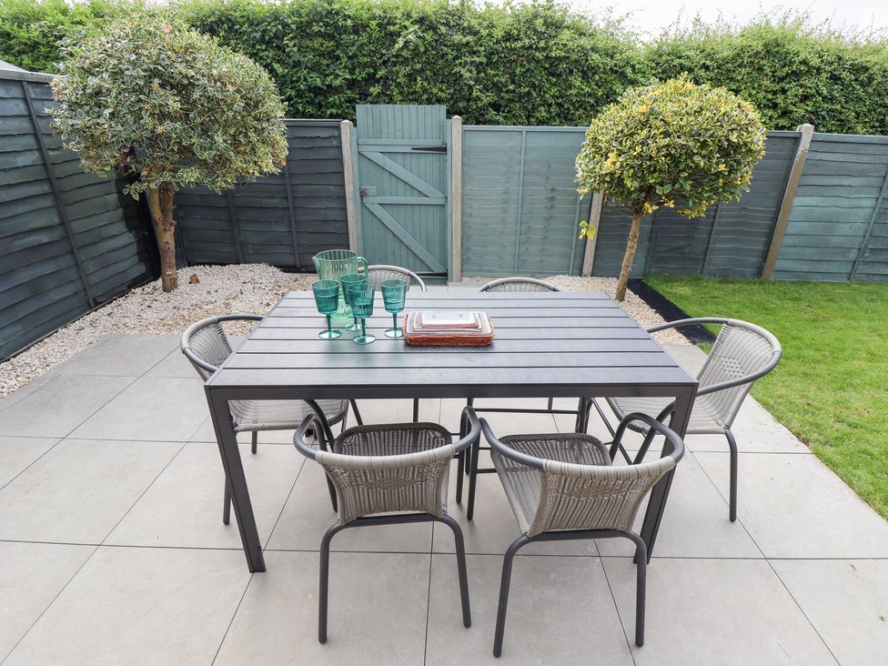 A garden with a table and chairs at Sandy Toes in Trusthorpe