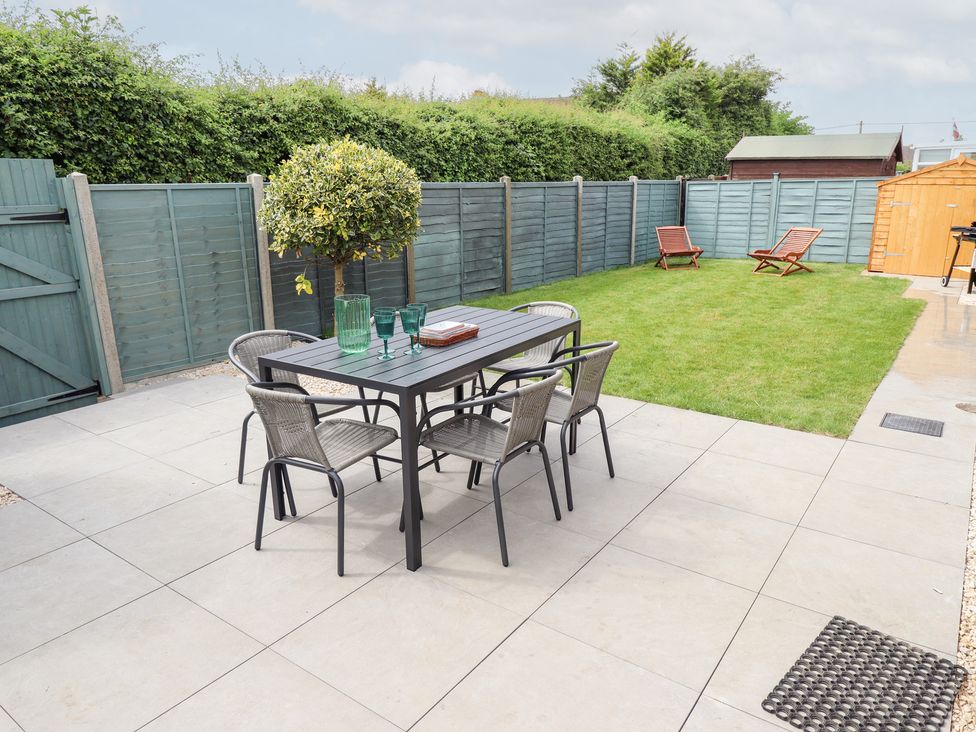 A garden with a table and chairs at Sandy Toes in Trusthorpe