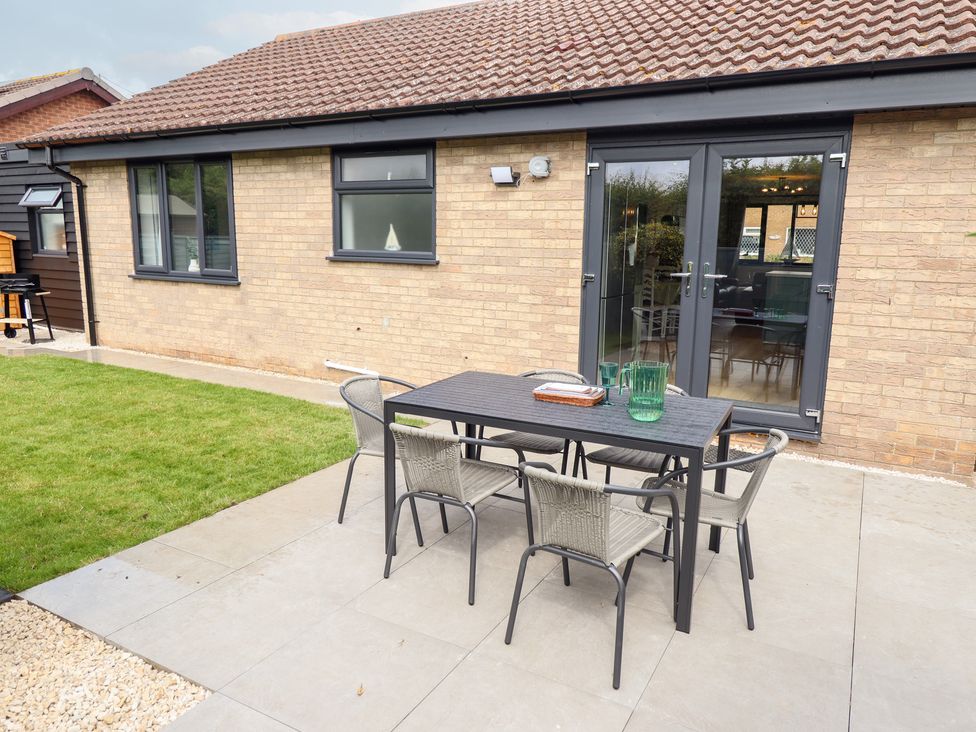 A garden with a table and chairs at Sandy Toes in Trusthorpe