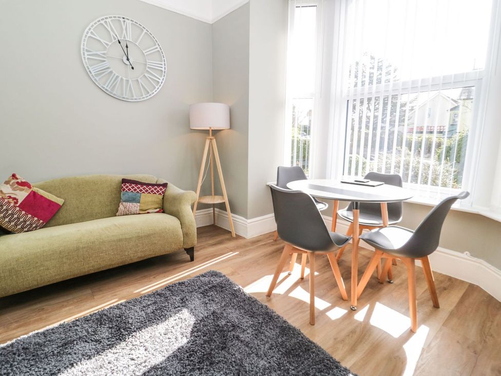 A living room with a clock on the wall at Flat 1A, Mona House in Conwy