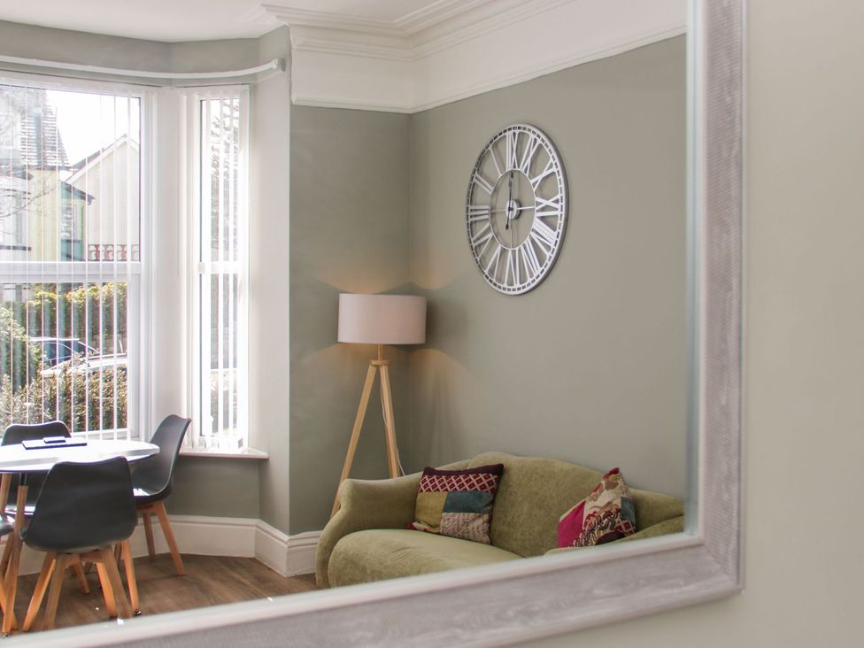 A living room with a sofa and floor lamp at Flat 1A, Mona House in Conwy