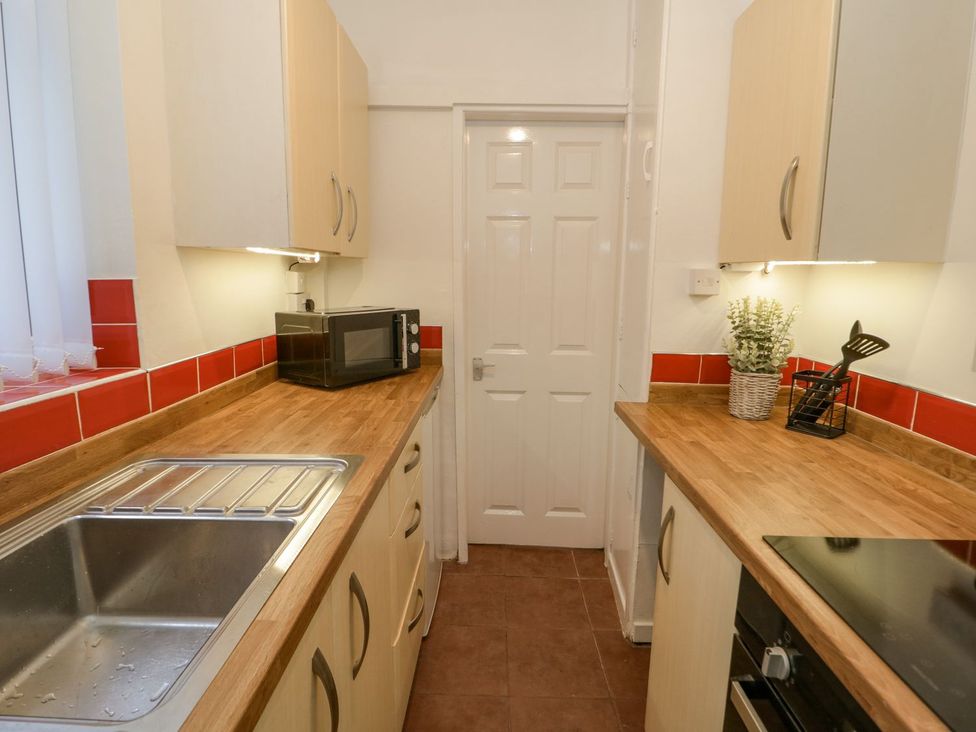 A kitchen with sink and microwave at Flat 1A, Mona House in Conwy