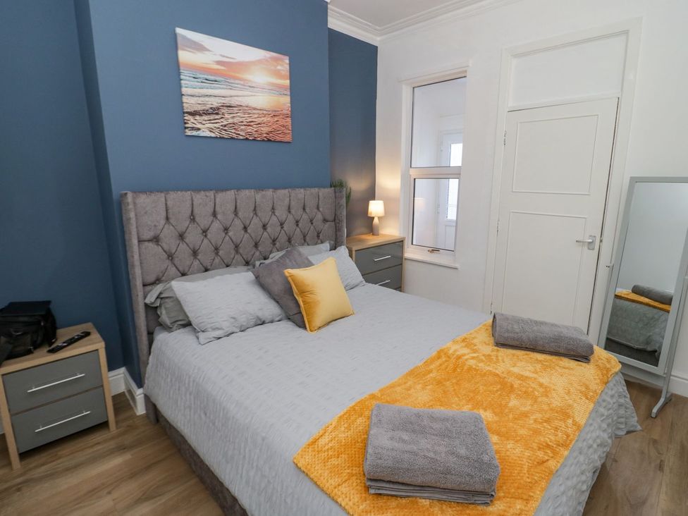 A bedroom featuring a bed, bedside table, and window at Flat 1A, Mona House in Conwy
