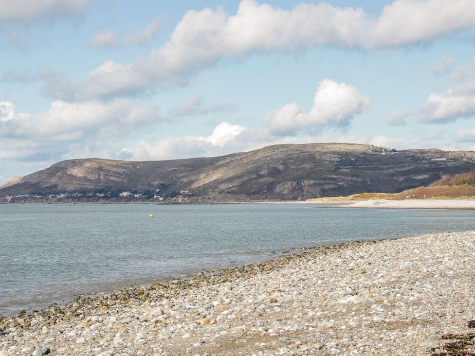 A beach scene with water and mountains at Flat 1A, Mona House in Conwy