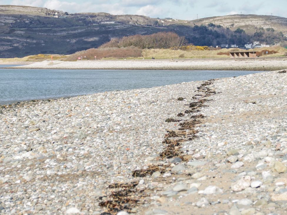 A beach with pebbles and seaweed at Flat 1A, Mona House in Conwy