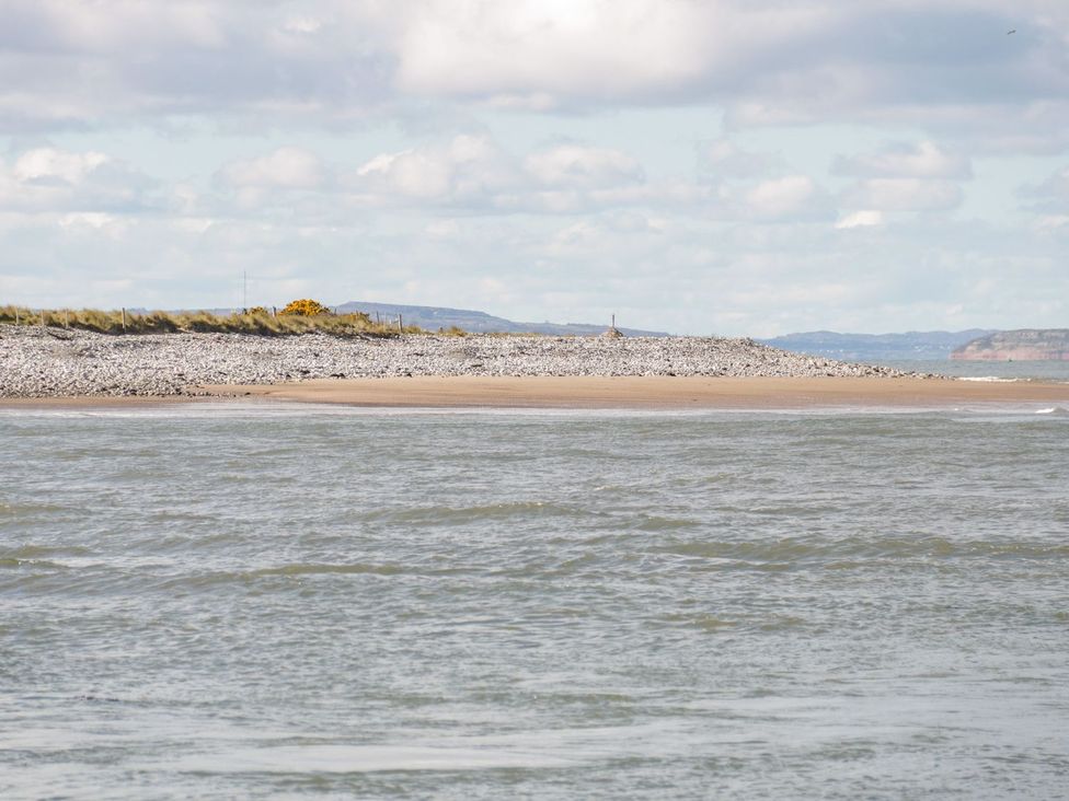 A beach with rocks and distant hills at Flat 1A, Mona House in Conwy