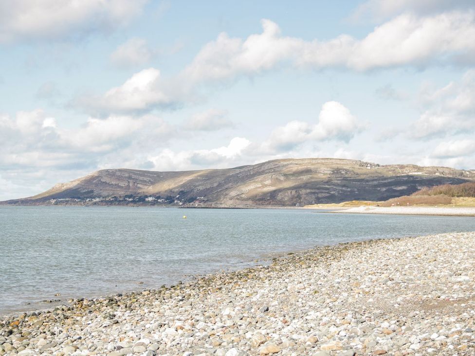 A beach with pebbles and mountains in the background at Flat 1A, Mona House in Conwy