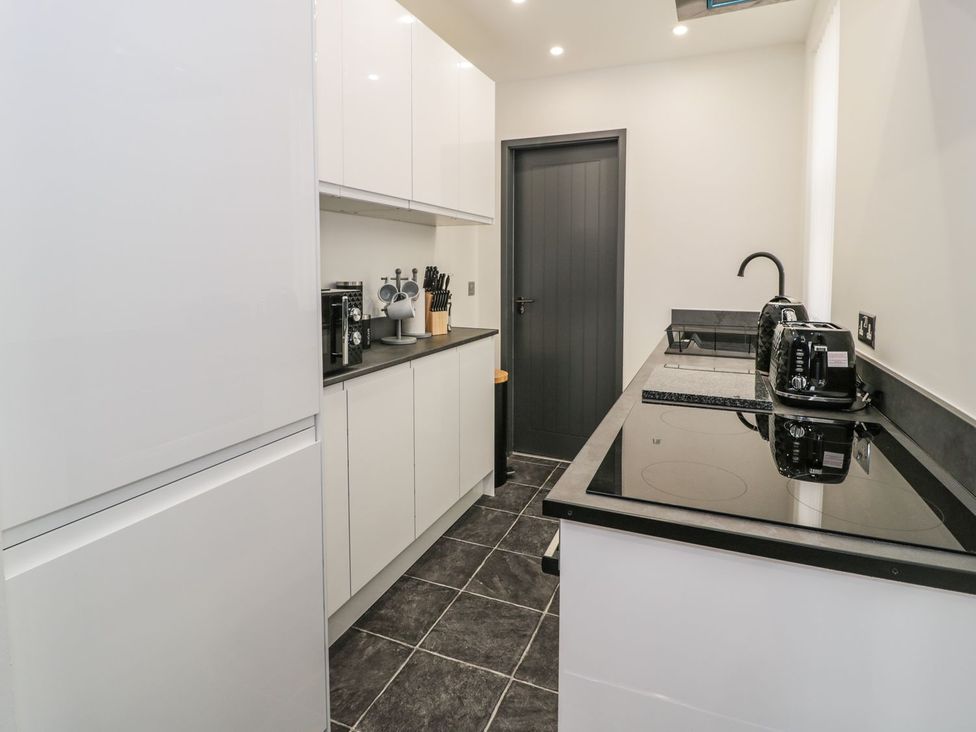 A kitchen with cabinets and appliances at Flat 1, Mona House in Conwy