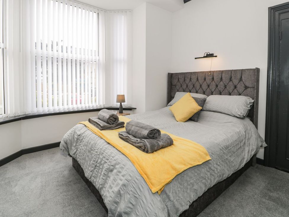 A bedroom with a bed and towels at Flat 1, Mona House in Conwy
