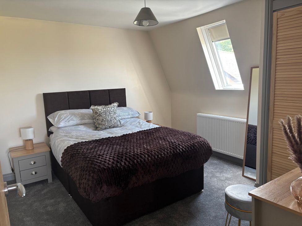 A bedroom with a bed, bedside table, and mirror at Hayes Lodge Coach House, Chulmleigh