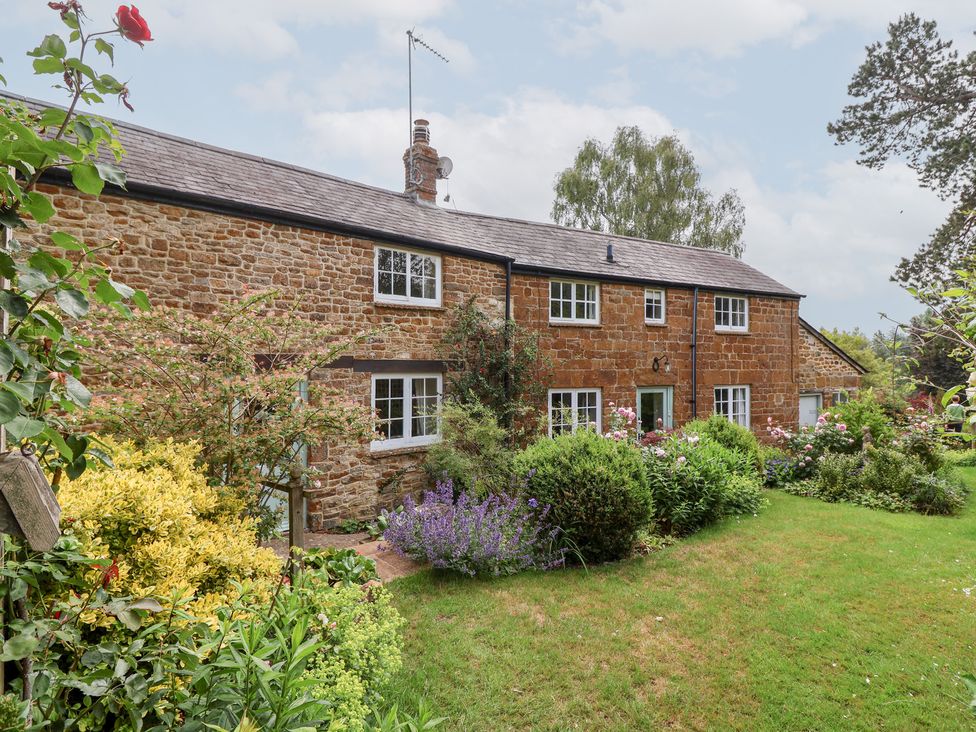 A brick house with garden and plants at Magdalen Cottage, Hook Norton