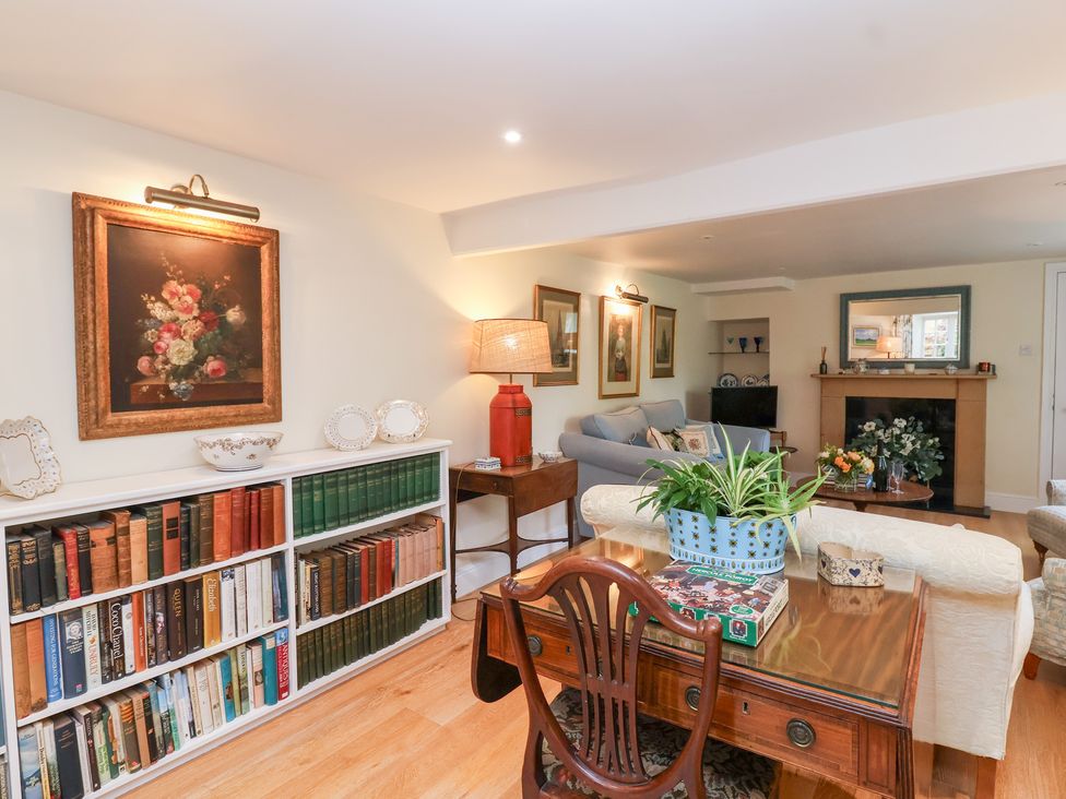 A living room with bookshelves and a sofa at Magdalen Cottage in Hook Norton