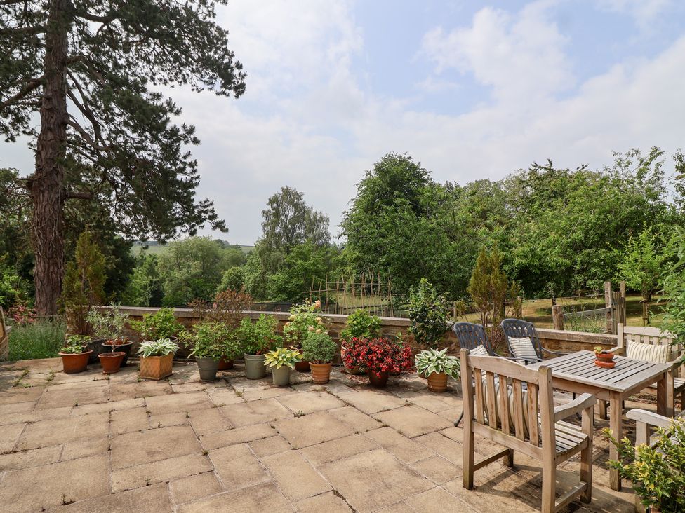 A garden with potted plants and patio furniture at Magdalen Cottage in Hook Norton