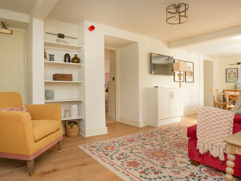 A living room with a sofa, armchair, and shelving at Apartment 1, 86 Dyer Street Cirencester