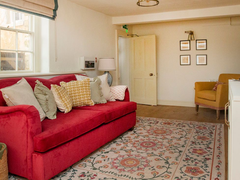 A living room with a red sofa and yellow chair at Apartment 1, 86 Dyer Street Cirencester