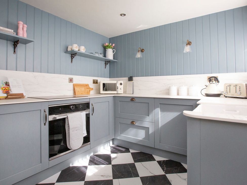 A kitchen with blue walls and modern appliances at Apartment 1, 86 Dyer Street in Cirencester