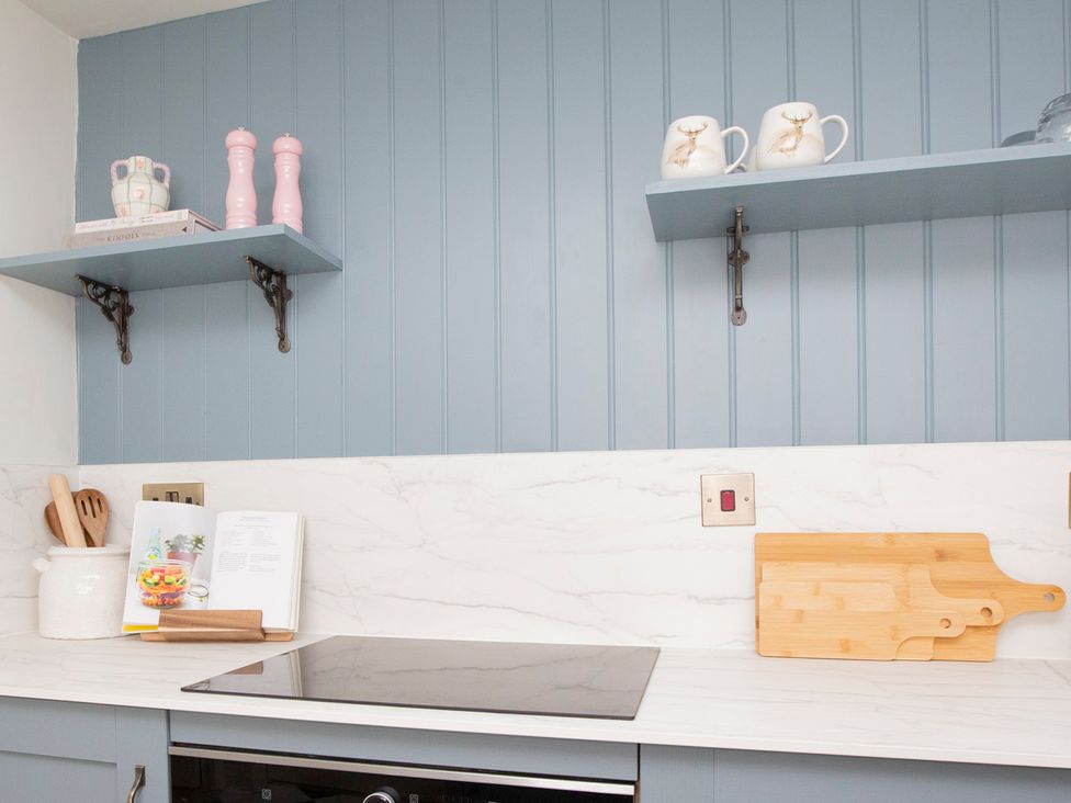A kitchen with countertop and shelves holding utensils at Apartment 1, 86 Dyer Street, Cirencester