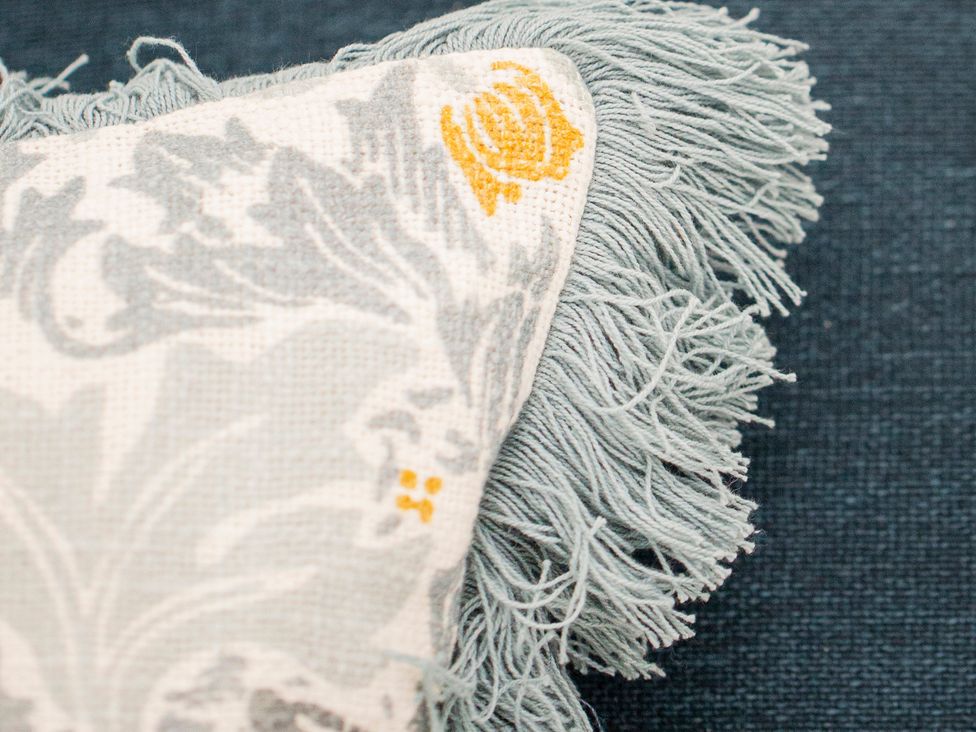 A close-up of a decorative cushion with fringes at Apartment 1, 86 Dyer Street in Cirencester